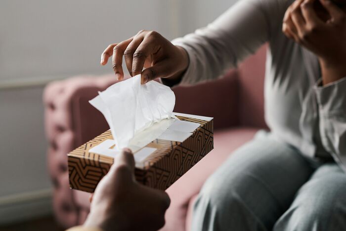 Hand reaching for a tissue from a box, illustrating ingenious inventions that found new purposes over the years.