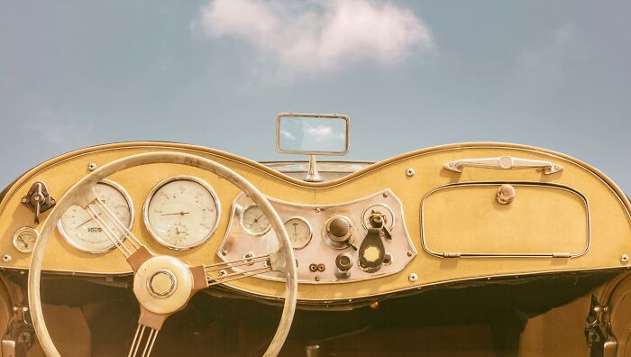 Vintage car dashboard with dials and steering wheel showcasing ingenious inventions repurposed over the years.