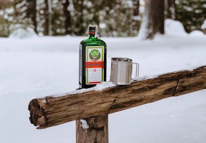 Green bottle and metal cup resting on a wooden beam in a snowy outdoor setting showcasing ingenious inventions repurposed over years