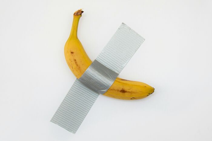 Banana taped to a white wall using duct tape, illustrating ingenious inventions that found new purposes over the years.