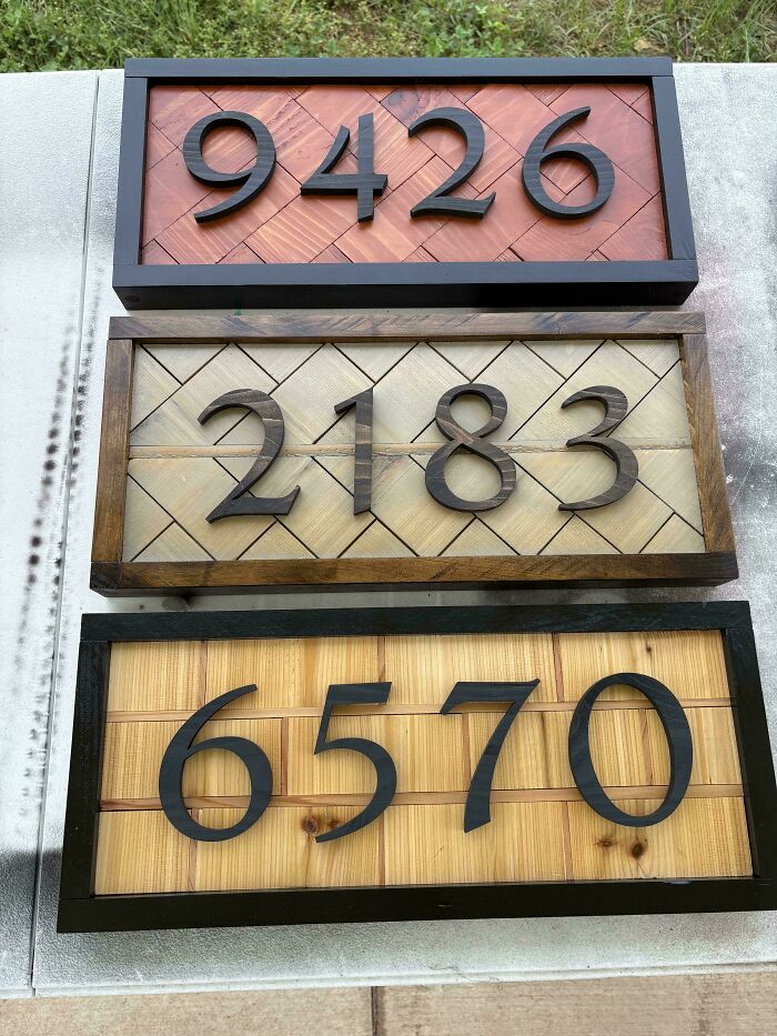 Three wood carved house number signs with black numbers on different wood backgrounds, showcasing woodworking projects.