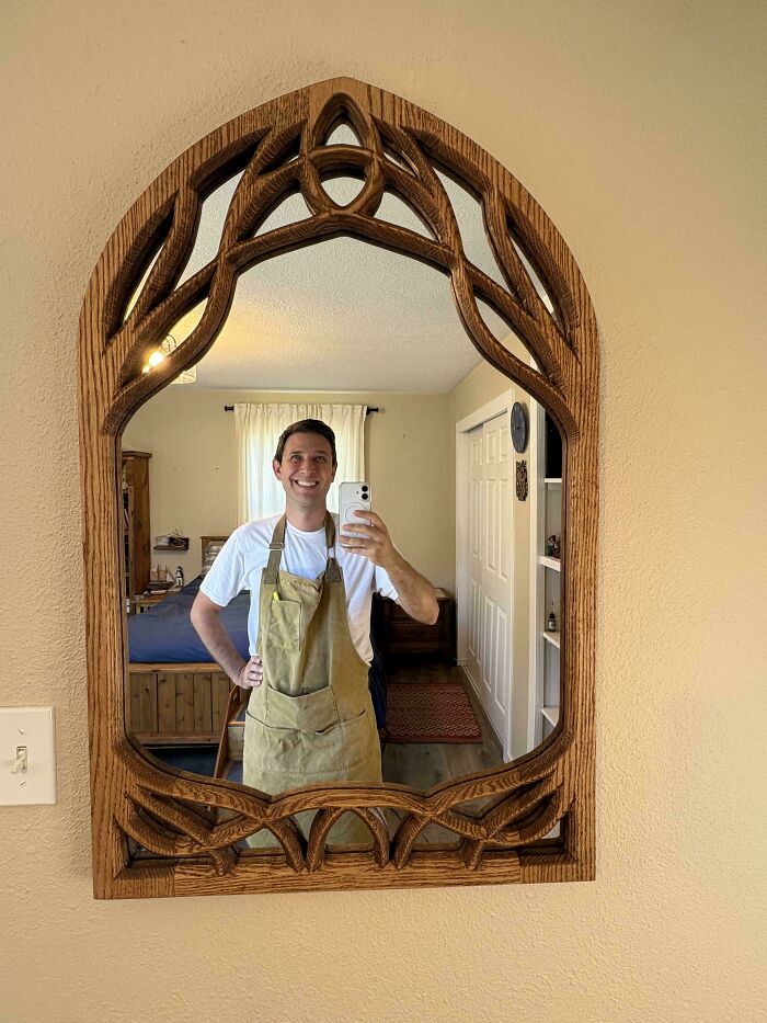 Woodworker taking a selfie in a beautifully carved wooden mirror frame showcasing incredible woodworking skills.