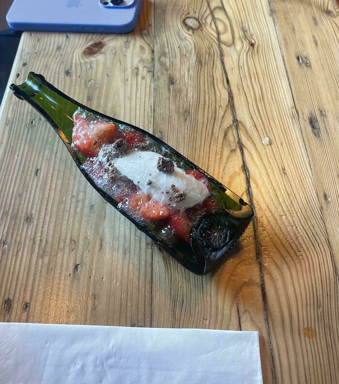 Food served inside a flattened glass bottle with toppings, showcasing one of the most ridiculous ways food is served in restaurants.