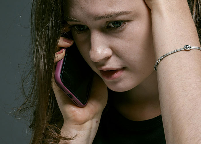 Worried woman on phone showing signs of fear and stress after a red-flag argument in her relationship. Worried woman on phone showing signs of fear and stress after a red-flag argument in her relationship.