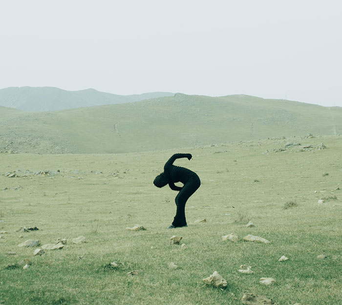 Person in full-body cat suit crawling on grassy field with hills, embodying mysterious figure terrorizing neighborhood at night. Person in full-body cat suit crawling on grassy field with hills, embodying mysterious figure terrorizing neighborhood at night.