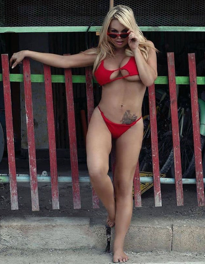 Woman in a red bikini posing by a red wooden fence, highlighting adult industry mental health substance-related issues. Woman in a red bikini posing by a red wooden fence, highlighting adult industry mental health substance-related issues.