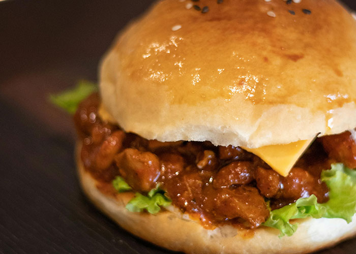 Close-up of a sloppy joe sandwich with cheese and lettuce, illustrating bizarre family food habits shared by 78 people.
