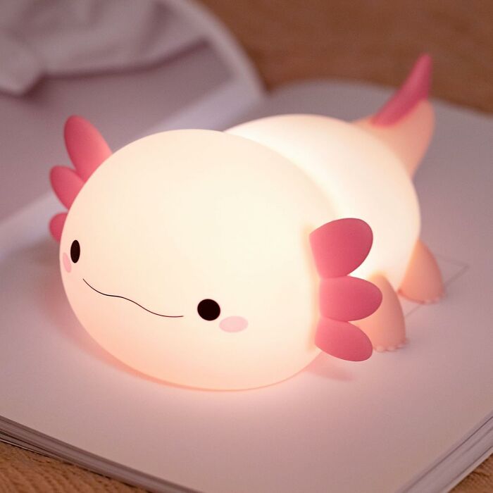 Cute glowing axolotl night light on book, showcasing one of the weirdest picks found on Amazon. Cute glowing axolotl night light on book, showcasing one of the weirdest picks found on Amazon.