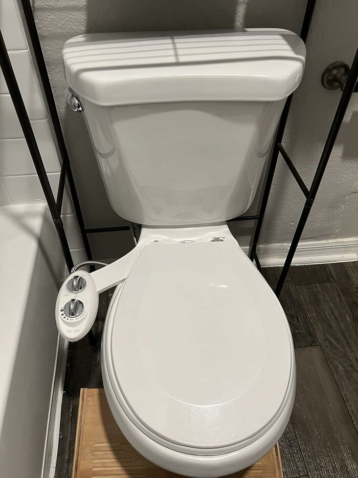 White toilet with bidet attachment featuring control knobs, an under-the-radar find for bathroom upgrade and comfort.