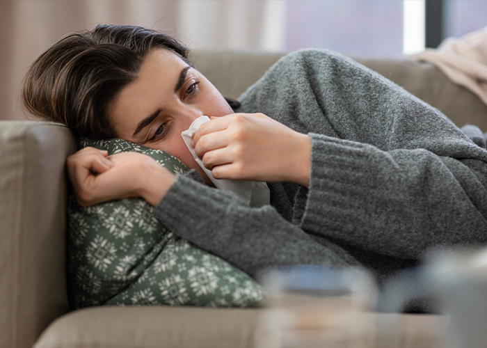 Young woman lying on couch with tissue, showing fatigue and frustration, illustrating facts people are tired of explaining.