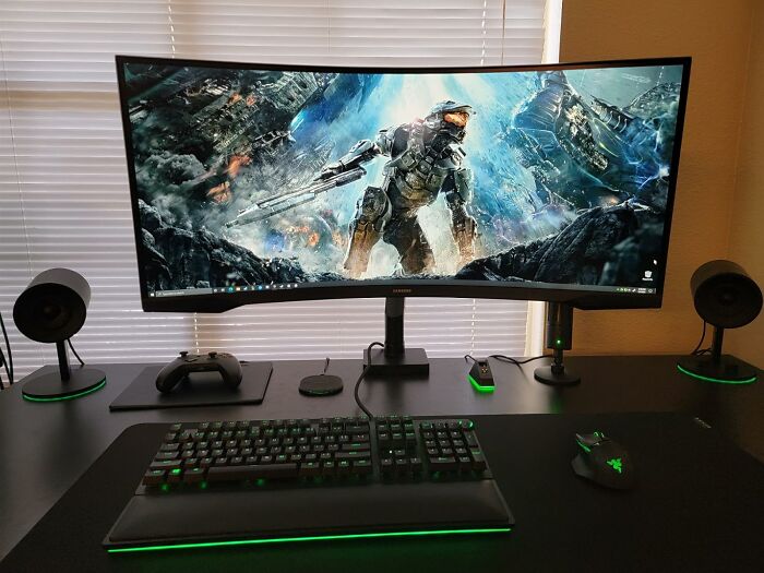 Curved ultrawide monitor setup with gaming keyboard, mouse, and speakers showcasing electronic deals for Prime Day shoppers.