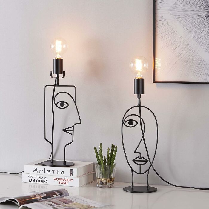 Abstract face wireframe lamps with exposed bulbs on a table, adding fun and unique home decor style.