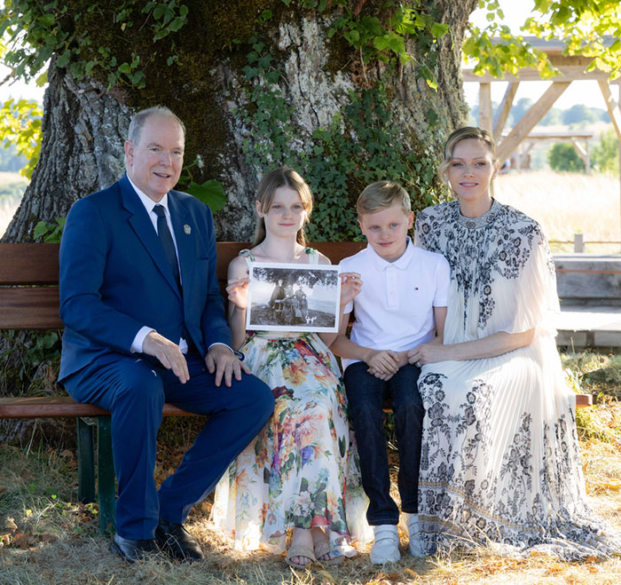 Grace Kelly’s granddaughter wearing a timeless dress, seated with family outdoors at a charity event. Grace Kelly’s granddaughter wearing a timeless dress, seated with family outdoors at a charity event.