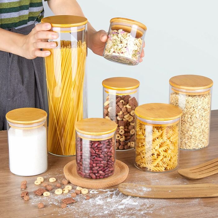 Clear glass kitchen storage containers with wooden lids holding pasta, cereal, and beans, ideal kitchen items worth counter space.