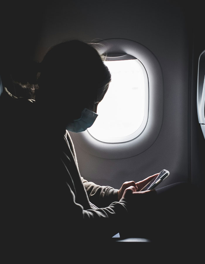 Passenger wearing a mask reading phone on flight near window, sparking scare and causing emergency landing. Passenger wearing a mask reading phone on flight near window, sparking scare and causing emergency landing.