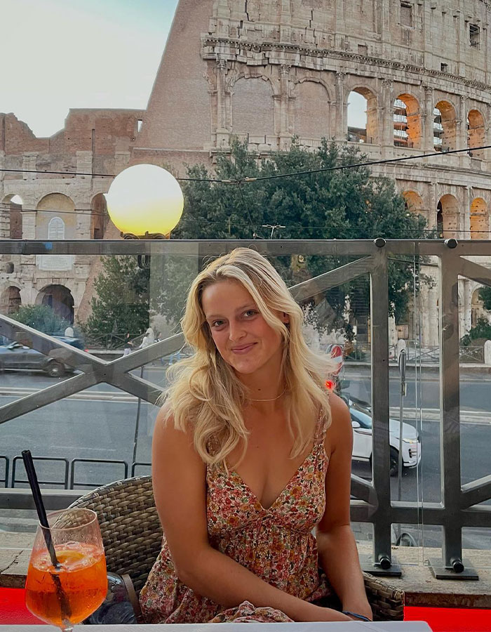 Young surf instructor with blonde hair sitting at outdoor cafe near historic Roman Colosseum in evening light. Young surf instructor with blonde hair sitting at outdoor cafe near historic Roman Colosseum in evening light.