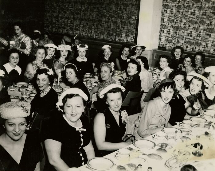 Vintage photo of nurses dressed elegantly, gathered around a long table, representing healing and hope in healthcare history.