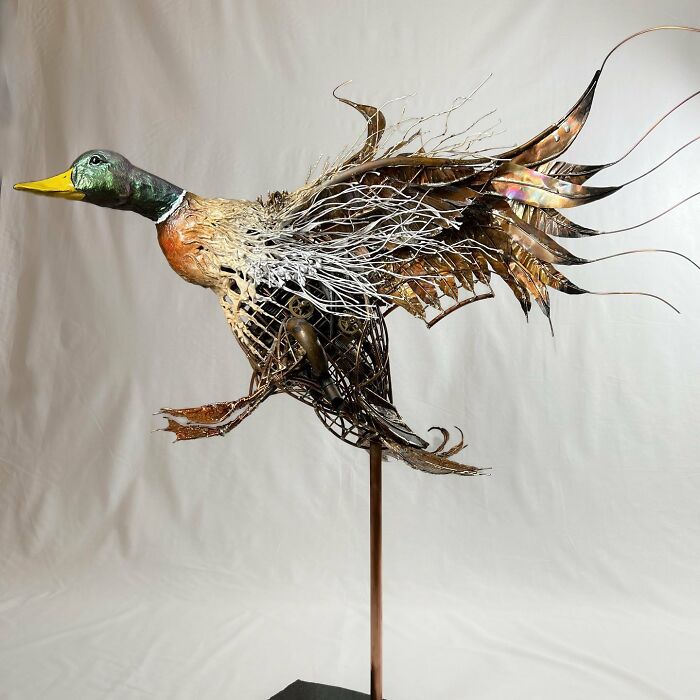 Sculpture of a flying duck made from scrap metal showcasing striking animal sculptures by an innovative artist.