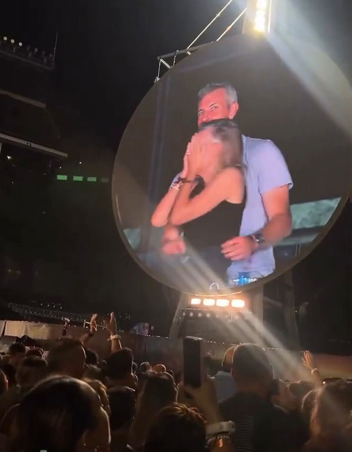 Couple shown on a large screen at a concert, crowd watching during a viral Coldplay frontman and Gwyneth Paltrow drama. Couple shown on a large screen at a concert, crowd watching during a viral Coldplay frontman and Gwyneth Paltrow drama.