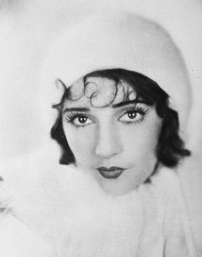 Black and white portrait of a woman from a century-old photo showcasing timeless beauty and vintage fashion.