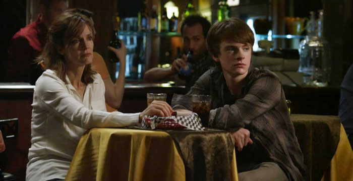 Two people sitting at a dimly lit bar table, engaging in conversation, reflecting a nepo baby family dynamic. Two people sitting at a dimly lit bar table, engaging in conversation, reflecting a nepo baby family dynamic.