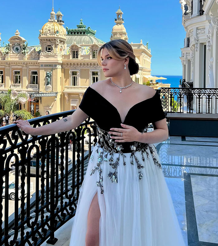 Grace Kelly’s granddaughter wearing a black and white elegant gown with jewelry at a luxury charity event balcony. Grace Kelly’s granddaughter wearing a black and white elegant gown with jewelry at a luxury charity event balcony.