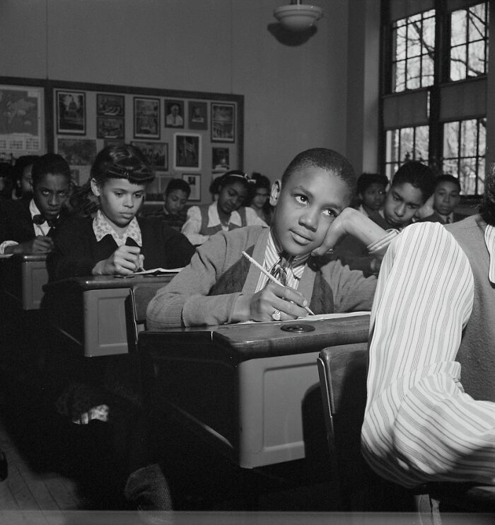 Students in a classroom during World War II, focused on writing and learning in a historic school environment.