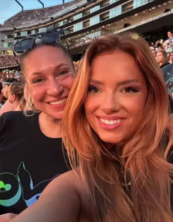 Two smiling women at a Coldplay concert, one wearing sunglasses, with a large crowd and stadium background. Two smiling women at a Coldplay concert, one wearing sunglasses, with a large crowd and stadium background.