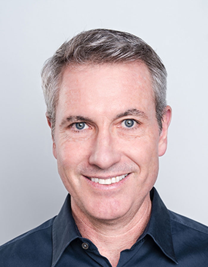 Middle-aged man smiling in a dark shirt, representing Coldplay fan who exposed cheating CEO by filming kiss cam. Middle-aged man smiling in a dark shirt, representing Coldplay fan who exposed cheating CEO by filming kiss cam.
