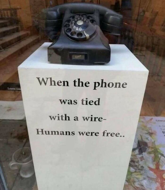 Vintage rotary phone displayed with a sign reflecting on the good old days of the 1980s and wired phone use.