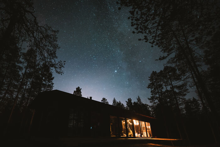 Cabin in the woods at night with glowing windows under a starry sky, offering a peaceful and true home retreat. Cabin in the woods at night with glowing windows under a starry sky, offering a peaceful and true home retreat.
