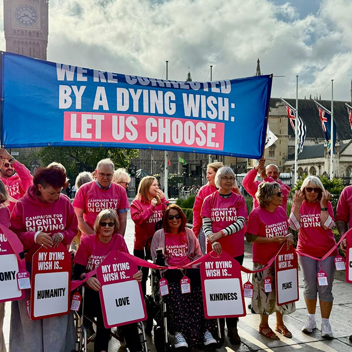 Group of activists wearing pink shirts holding signs about dignity in dying during a public demonstration for dying wish rights. Group of activists wearing pink shirts holding signs about dignity in dying during a public demonstration for dying wish rights.