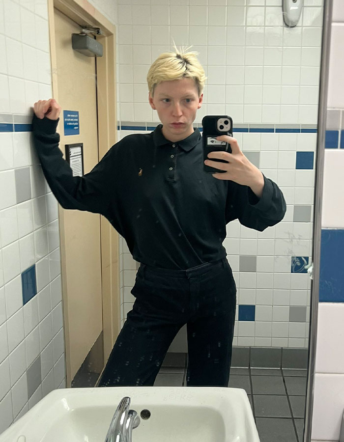 Young model taking a mirror selfie in a bathroom, reflecting on transition and detransition experiences. Young model taking a mirror selfie in a bathroom, reflecting on transition and detransition experiences.
