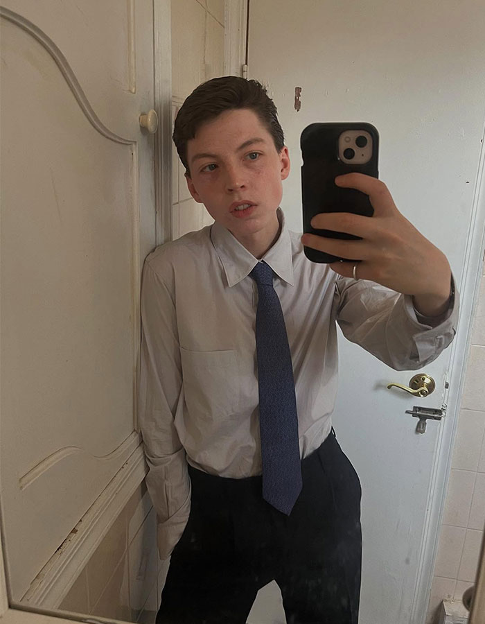 Model taking a mirror selfie wearing a shirt and tie, reflecting on detransition after transition at age 15. Model taking a mirror selfie wearing a shirt and tie, reflecting on detransition after transition at age 15.