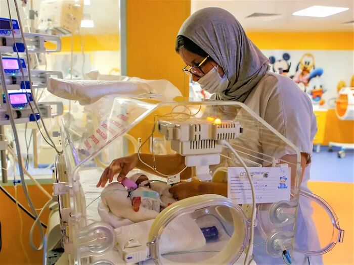 Nurse caring for the world’s first surviving nonuplets baby in a hospital incubator with medical monitoring equipment nearby Nurse caring for the world’s first surviving nonuplets baby in a hospital incubator with medical monitoring equipment nearby