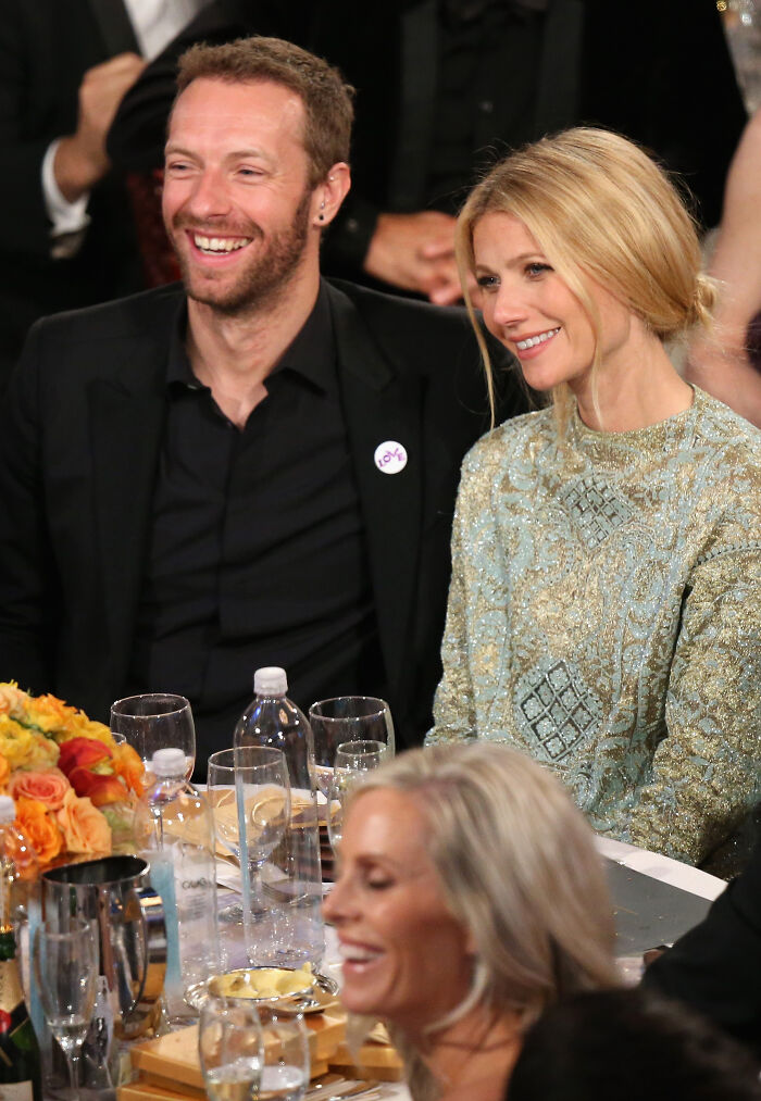 Coldplay frontman and Gwyneth Paltrow seated at event table, sharing a moment amid viral drama discussion. Coldplay frontman and Gwyneth Paltrow seated at event table, sharing a moment amid viral drama discussion.