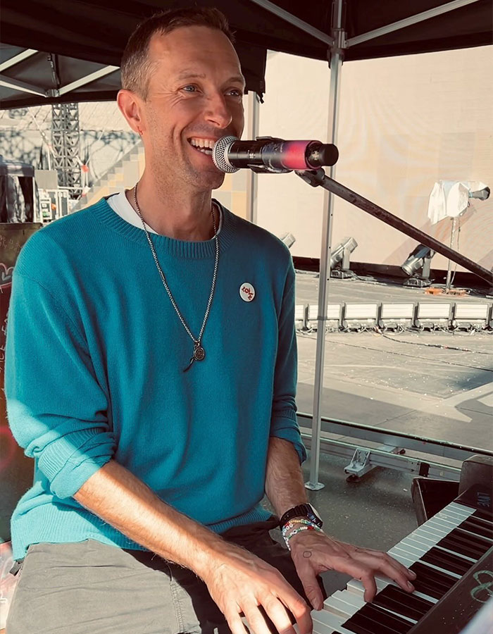 Coldplay frontman performing on piano and singing into a microphone during an outdoor rehearsal session. Coldplay frontman performing on piano and singing into a microphone during an outdoor rehearsal session.