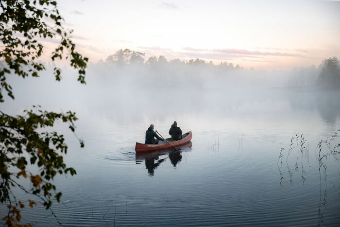 Two people paddling a canoe on a misty lake near a cabin in the woods, embracing peaceful nature and solitude. Two people paddling a canoe on a misty lake near a cabin in the woods, embracing peaceful nature and solitude.