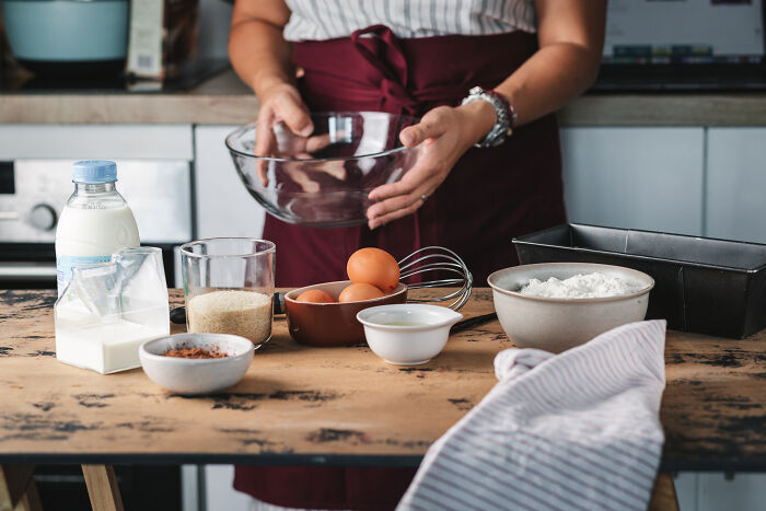 Person preparing ingredients on a wooden table for baking a childhood cake as a family remedy after a hospital trip. Person preparing ingredients on a wooden table for baking a childhood cake as a family remedy after a hospital trip.