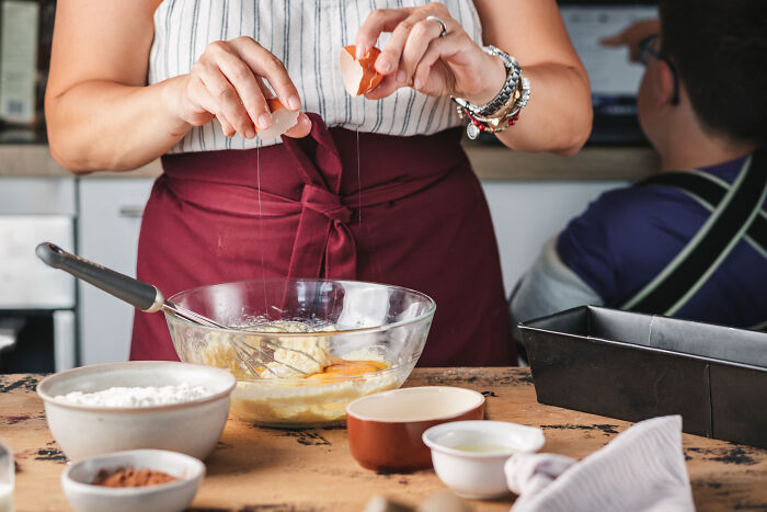 Person cracking eggs into a glass bowl while baking a childhood cake as a family remedy after hospital trip. Person cracking eggs into a glass bowl while baking a childhood cake as a family remedy after hospital trip.