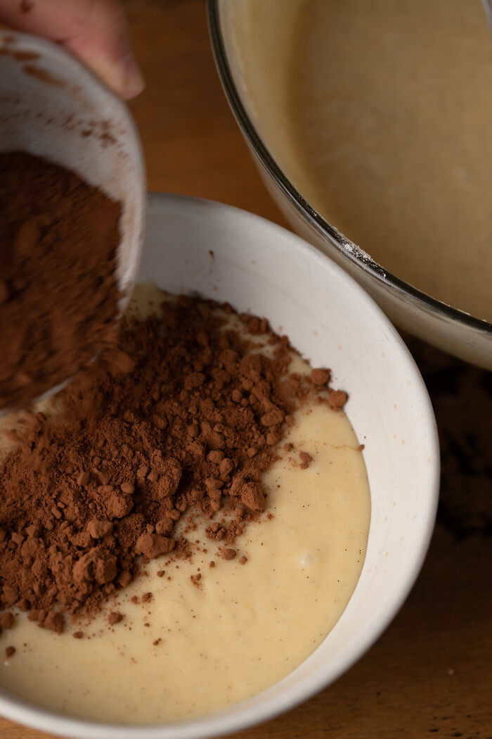 Baking childhood cake batter in a bowl with cocoa powder being added for a family remedy after hospital trip. Baking childhood cake batter in a bowl with cocoa powder being added for a family remedy after hospital trip.