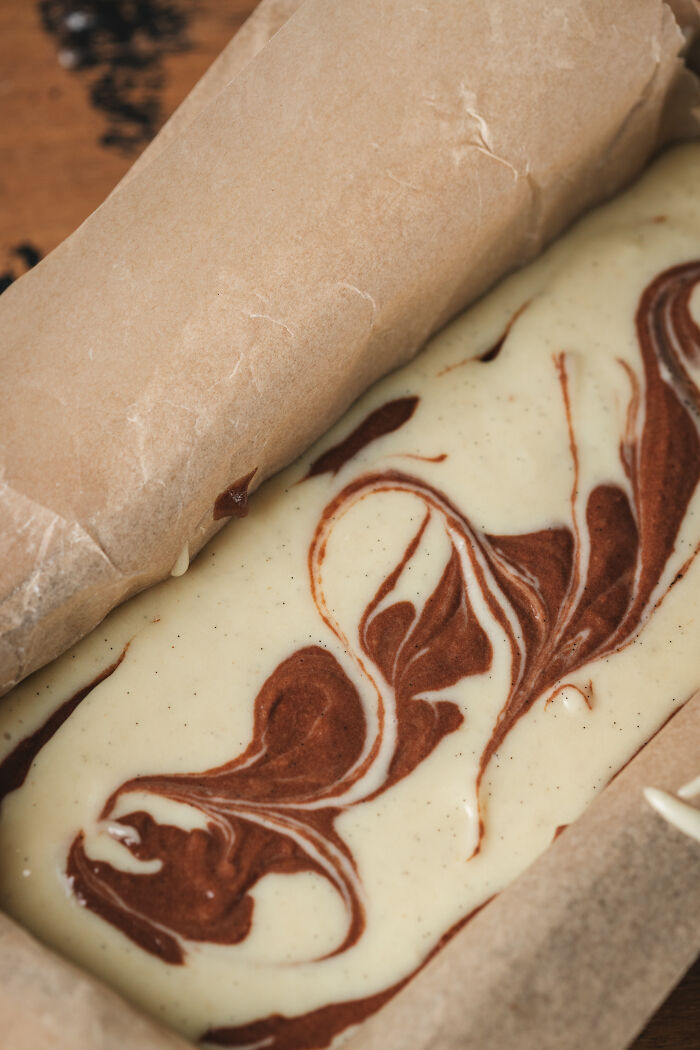 Marble cake batter in a parchment-lined pan, illustrating baking a childhood cake as an unexpected family remedy. Marble cake batter in a parchment-lined pan, illustrating baking a childhood cake as an unexpected family remedy.