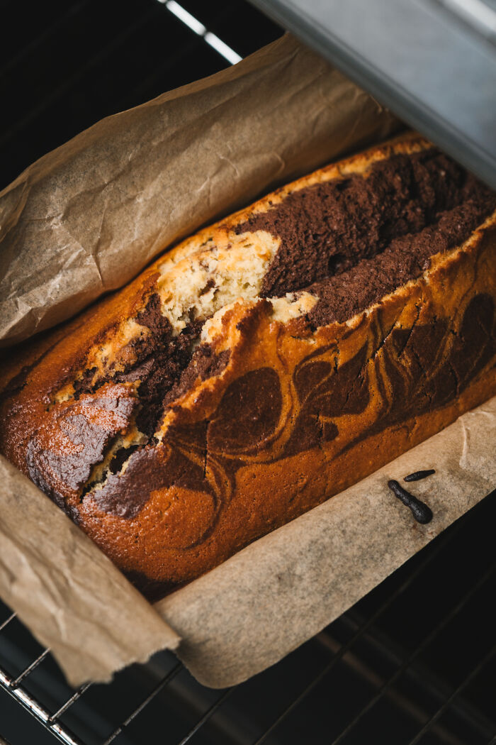 Marble cake baking in oven on parchment paper, symbolizing childhood cake as family’s unexpected remedy after son's hospital trip. Marble cake baking in oven on parchment paper, symbolizing childhood cake as family’s unexpected remedy after son's hospital trip.