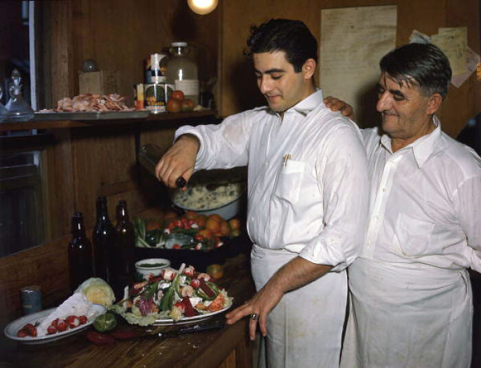 Two men preparing a salad in a kitchen offering a classic glimpse into everyday life in 1950s Florida.