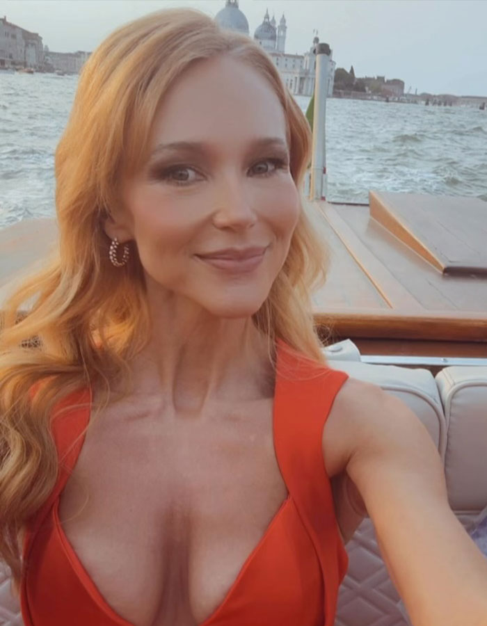 Jewel, 51, smiling in a low-cut red dress on a boat with water and historic buildings in the background. Jewel, 51, smiling in a low-cut red dress on a boat with water and historic buildings in the background.