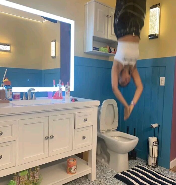 Person hanging upside down in a bathroom near a toilet, illustrating one of the cursed images found on the internet.