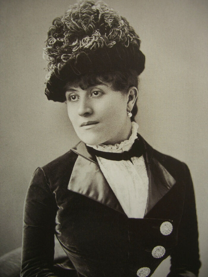 Victorian-era courtesan dressed in elegant attire and elaborate hat, representing courtesans who became power players in history.
