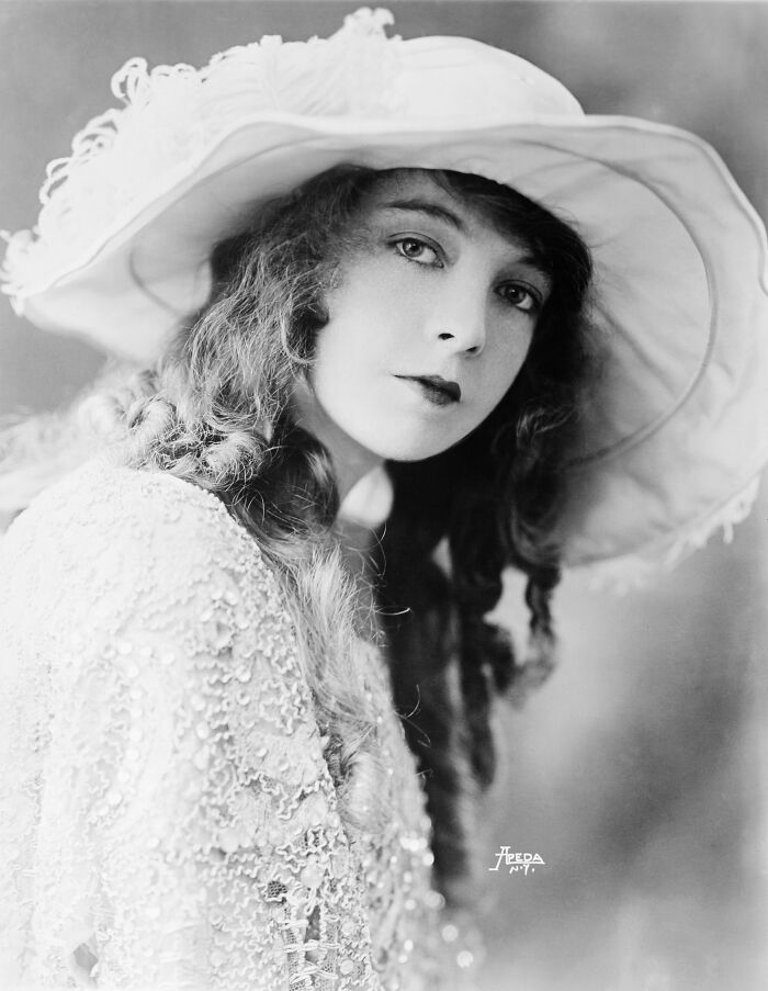 Black and white century-old photo of a woman wearing an elegant hat, embodying timeless beauty and classic fashion.