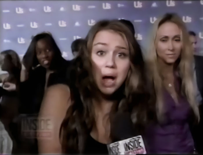 Miley Cyrus reacting during an old interview with reporters questioning her intimate life at age 14.