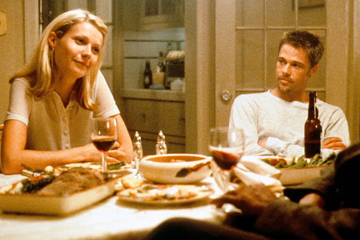 Gwyneth Paltrow and Brad Pitt seated at a dinner table with wine, sharing a quiet moment during their relationship. Gwyneth Paltrow and Brad Pitt seated at a dinner table with wine, sharing a quiet moment during their relationship.